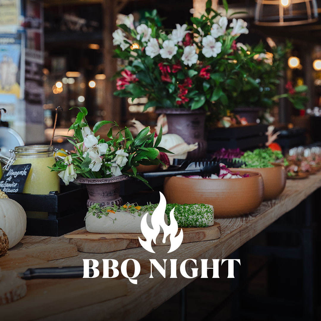 Arreglo floral y comida en la mesa de madera; logotipo de la Noche de la Barbacoa