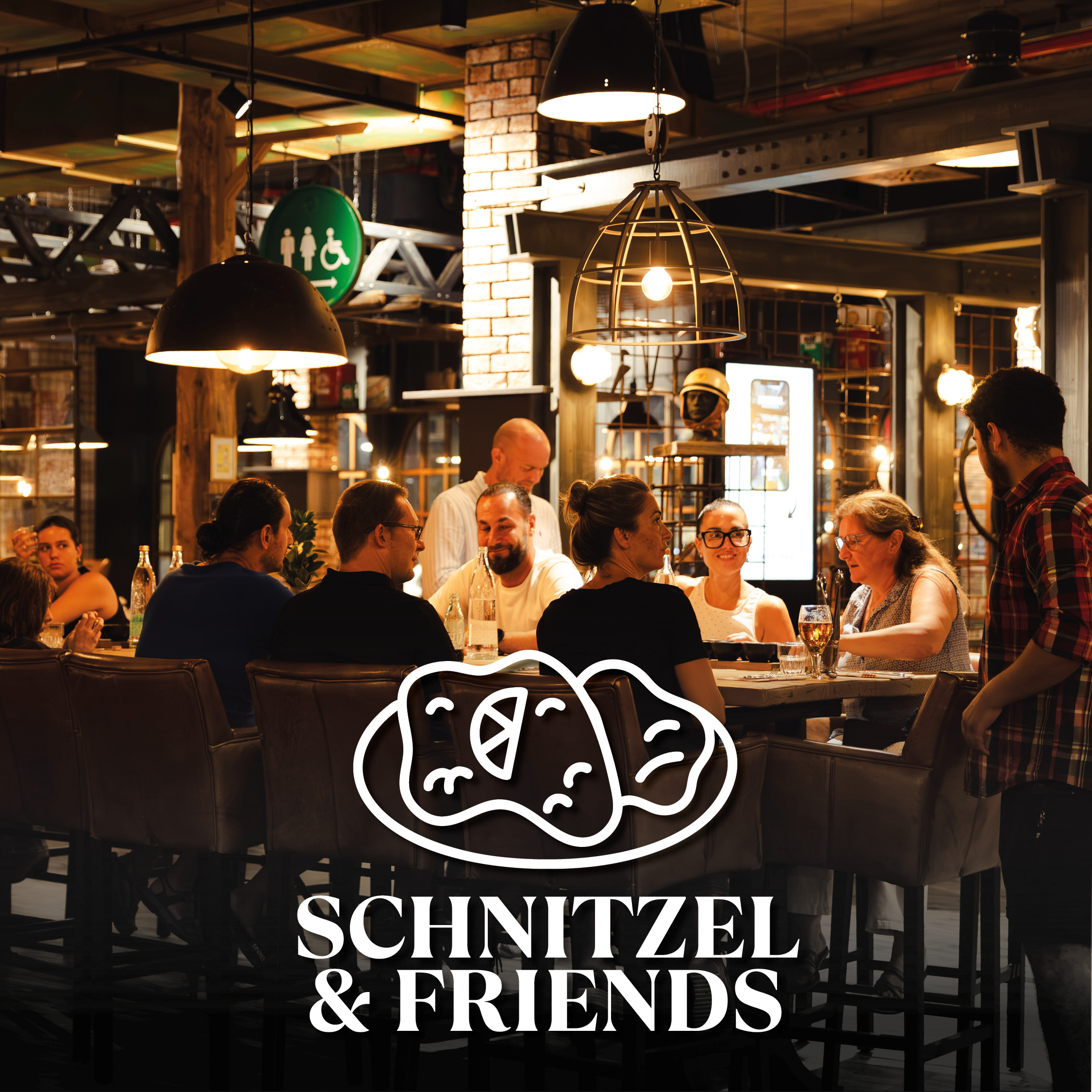 Eine Gruppe von Freunden sitzt gemütlich an einem langen Tisch in einem modern-industriellen Restaurant, während sie lachen und sich unterhalten; im Vordergrund prangt ein großes weißes Logo mit einer stilisierten Schnitzel-Illustration und dem Schriftzug SCHNITZEL & FRIENDS.