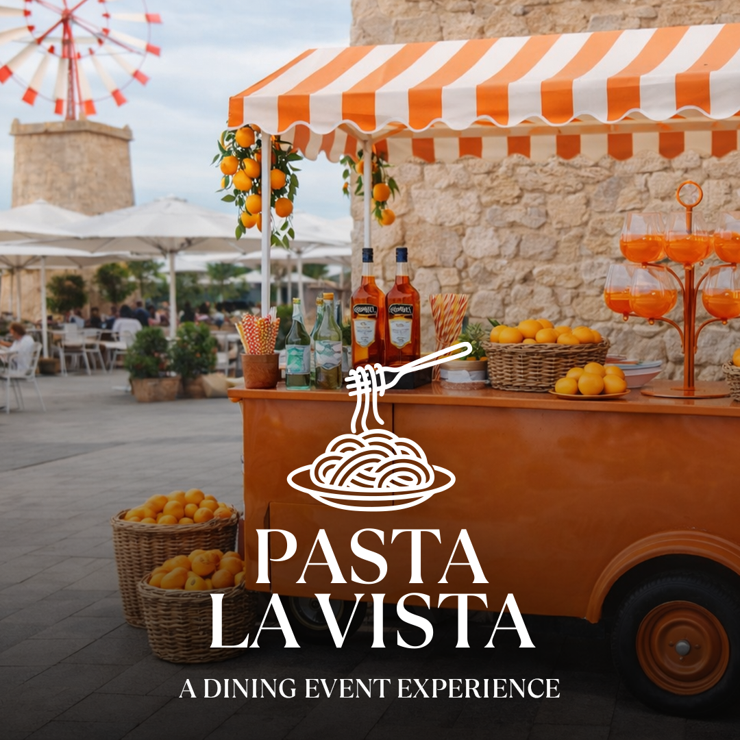 Orange basket, drinks stand with orange striped tent and Pasta La Vista logo, outdoor dining in front of stone wall with windmill.