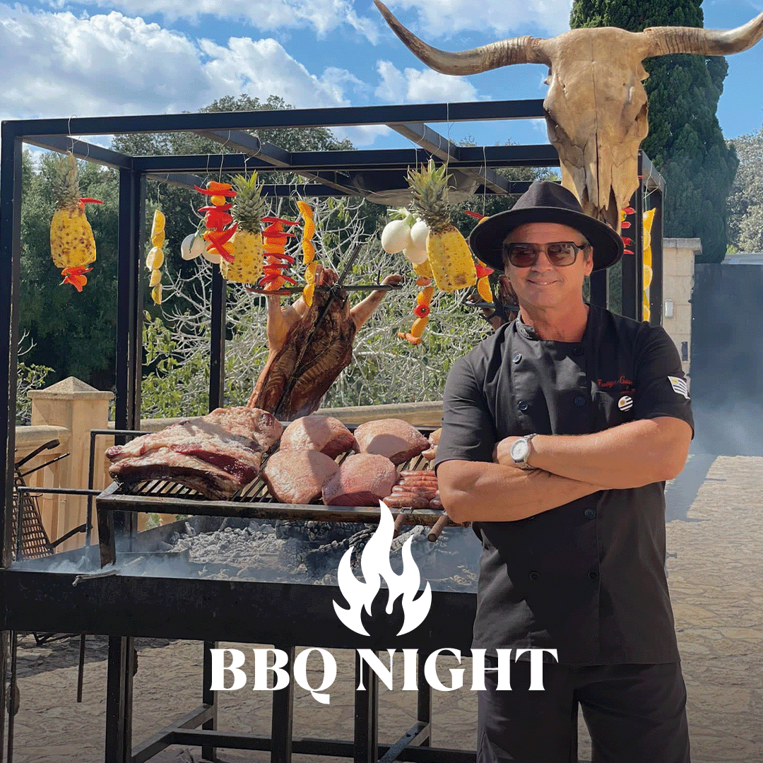 Maestro de barbacoa con delantal negro y sombrero junto a una barbacoa con grandes trozos de carne, brochetas de fruta colgando de un marco, calavera con cuernos encima, letras "BBQ Night".
